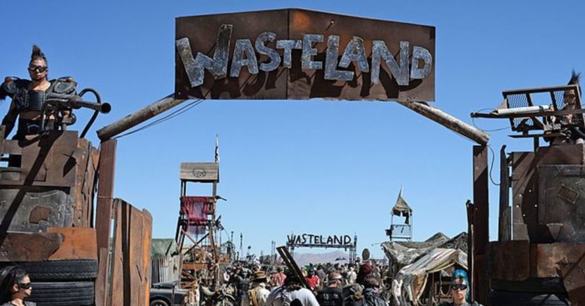 an entrance to a post apocalyptic city with guards on towers at the gate