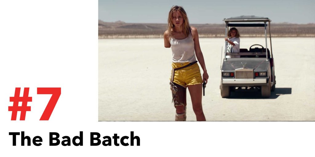 a girl with one arm stands in front of her gold cart in the desert